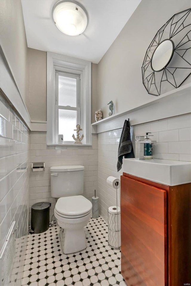 bathroom with tile patterned flooring, vanity, toilet, and tile walls