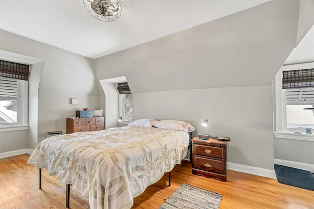 bedroom with lofted ceiling, wood-type flooring, and multiple windows