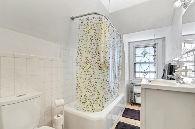 full bathroom with tile patterned flooring, toilet, shower / bath combo with shower curtain, vanity, and tile walls