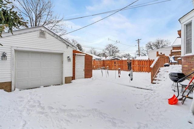 snowy yard featuring an outbuilding and a garage