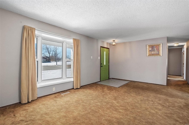 carpeted spare room with visible vents and a textured ceiling