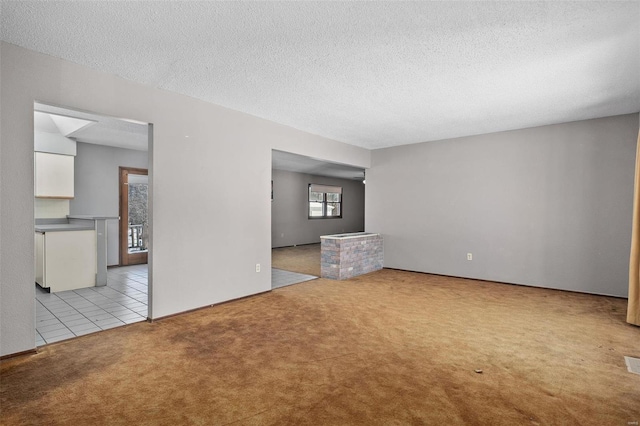 unfurnished living room featuring a textured ceiling, light tile patterned floors, visible vents, and light colored carpet