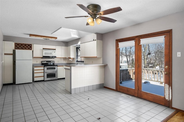 kitchen with a peninsula, white appliances, white cabinetry, light countertops, and a wealth of natural light