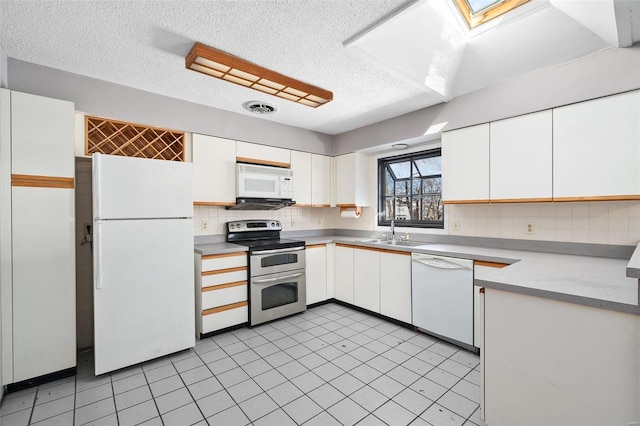 kitchen with white appliances, visible vents, white cabinets, light countertops, and a sink