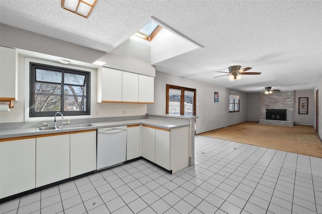 kitchen featuring white dishwasher, a sink, white cabinets, open floor plan, and light countertops