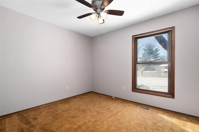 spare room featuring light carpet, ceiling fan, a textured ceiling, and visible vents