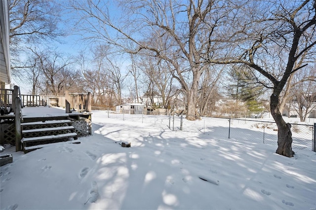 snowy yard featuring fence and a deck