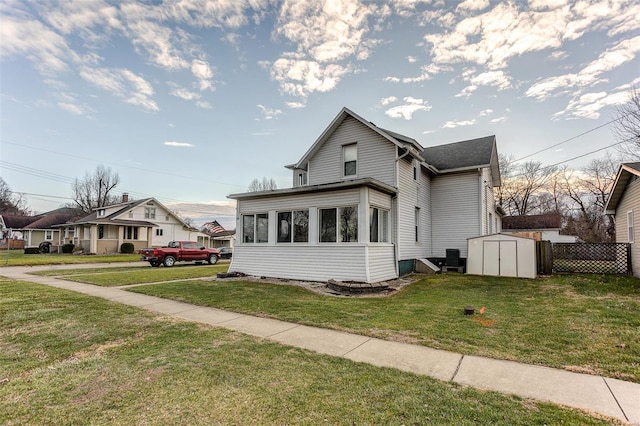 view of front of property featuring a front yard, a storage shed, and a sunroom