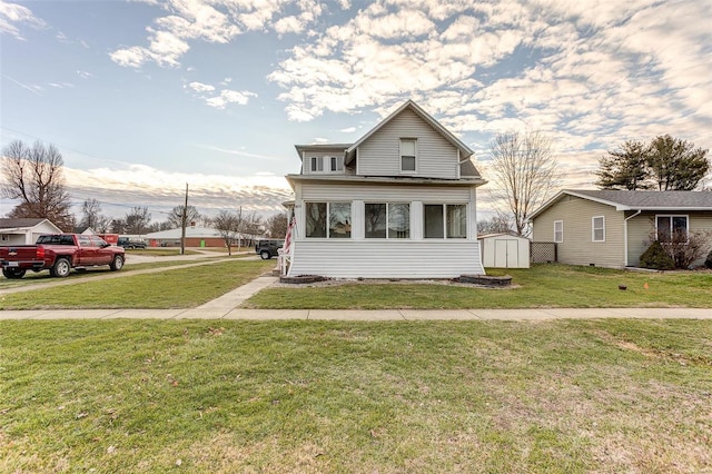 view of front of home with a sunroom, a front lawn, and a shed