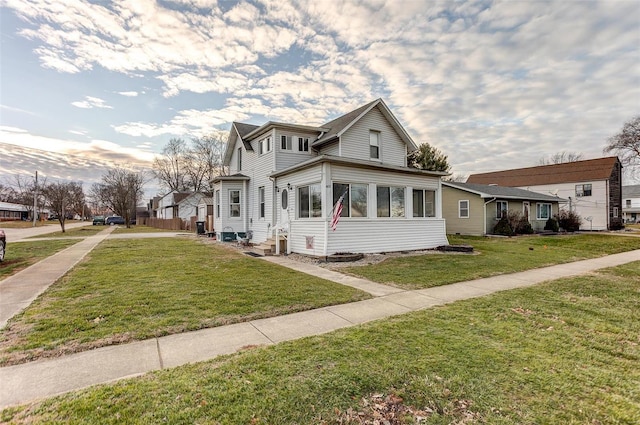 view of front of home featuring a sunroom and a front lawn