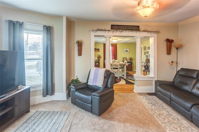 living room with decorative columns, ceiling fan, and carpet