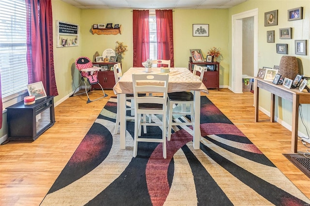 dining area with a drop ceiling and light hardwood / wood-style floors