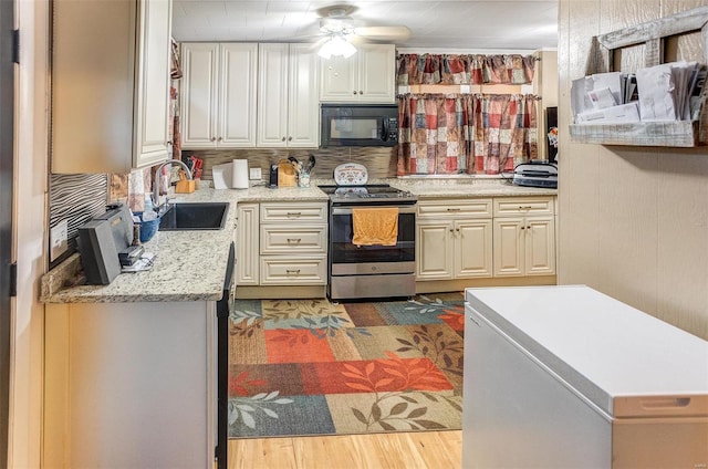 kitchen with light stone counters, ceiling fan, sink, electric range, and hardwood / wood-style flooring