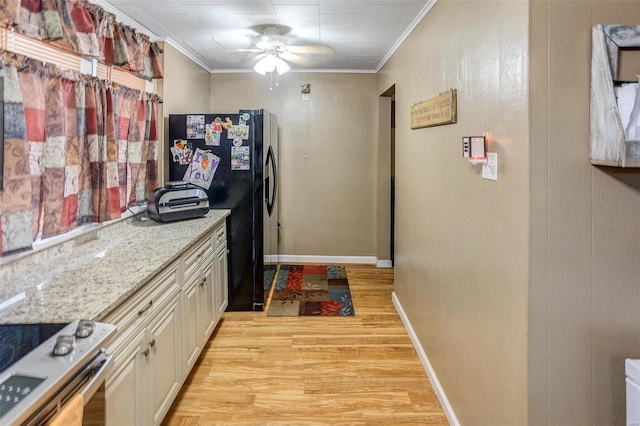 kitchen with light stone countertops, black fridge with ice dispenser, light hardwood / wood-style flooring, and ornamental molding