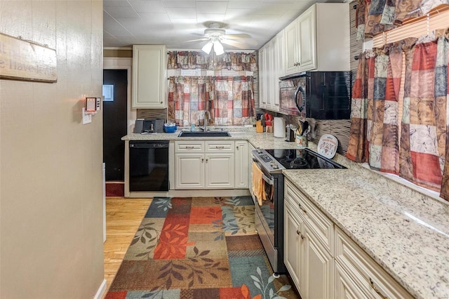 kitchen with ceiling fan, sink, light stone counters, light hardwood / wood-style floors, and black appliances