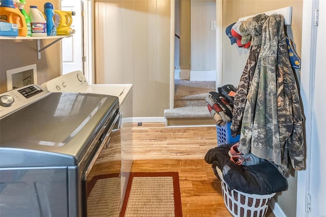 laundry room featuring wooden walls, washer and clothes dryer, and hardwood / wood-style floors