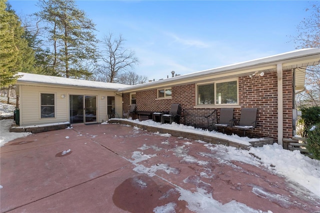 snow covered house featuring a patio area