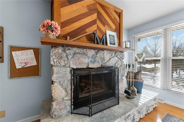 room details with hardwood / wood-style floors and a stone fireplace