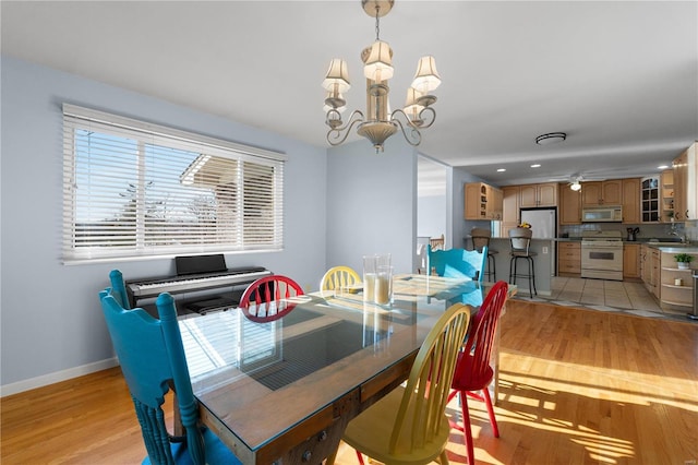 dining area featuring sink, a chandelier, and light hardwood / wood-style floors