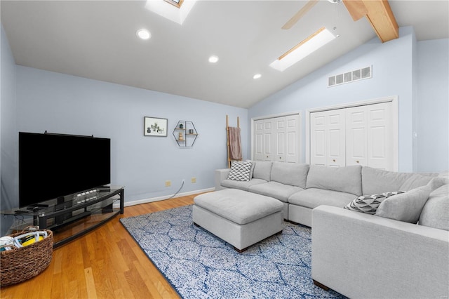 living room featuring lofted ceiling with skylight, wood-type flooring, and ceiling fan