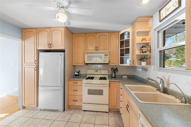 kitchen with light brown cabinetry, sink, white appliances, and light tile patterned floors