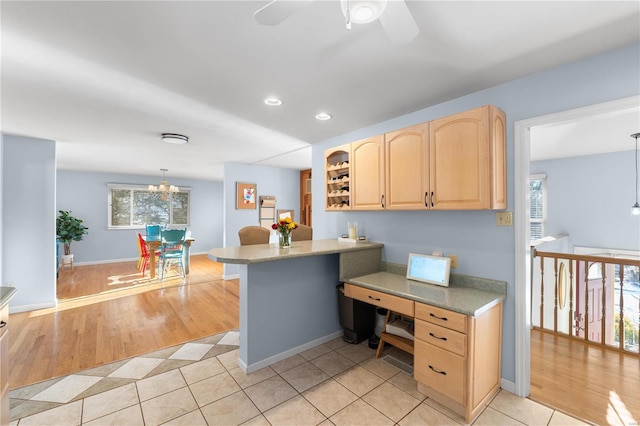 kitchen featuring kitchen peninsula, hanging light fixtures, light tile patterned floors, light brown cabinetry, and ceiling fan with notable chandelier