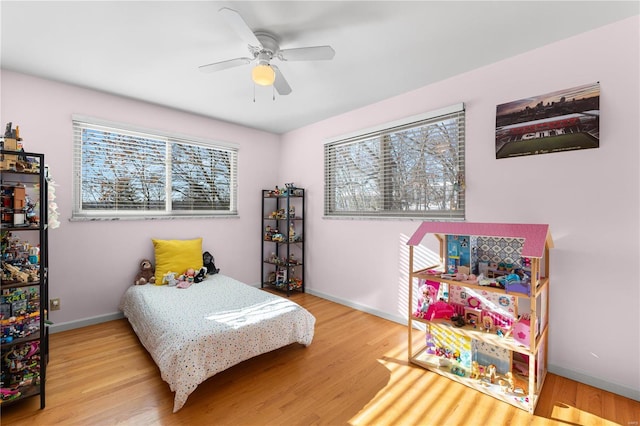 bedroom with ceiling fan, multiple windows, and hardwood / wood-style flooring