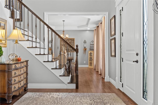 entrance foyer with an inviting chandelier, wood-type flooring, and a tray ceiling