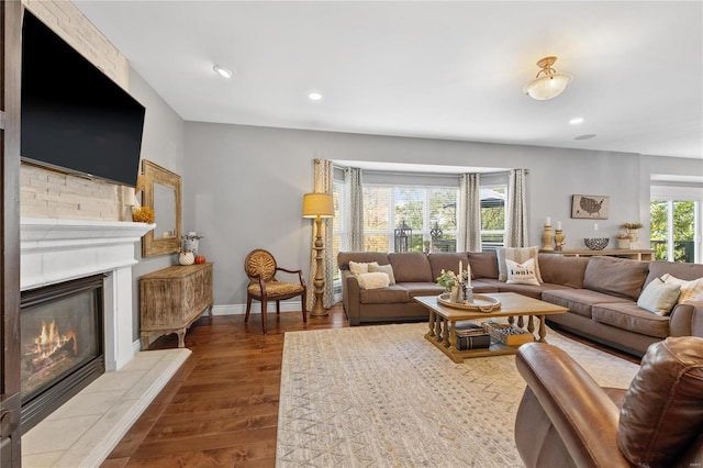 living room with plenty of natural light, wood-type flooring, and a tile fireplace