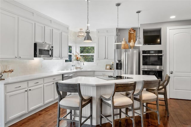 kitchen featuring decorative light fixtures, a kitchen island, stainless steel appliances, white cabinets, and dark hardwood / wood-style flooring