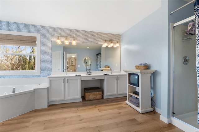 bathroom with plus walk in shower, hardwood / wood-style floors, and vanity