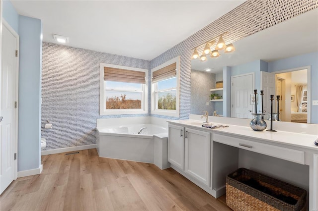 bathroom with toilet, vanity, wood-type flooring, and a bathtub