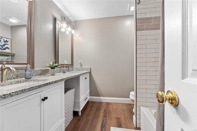 full bathroom with toilet, vanity, tiled shower / bath combo, and hardwood / wood-style flooring