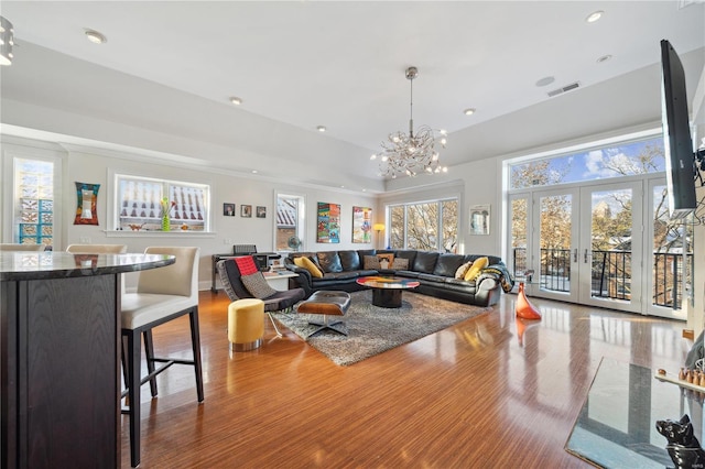 living room with french doors, a notable chandelier, and wood-type flooring