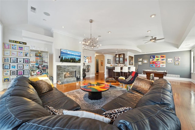 living room featuring a high end fireplace, ceiling fan with notable chandelier, crown molding, built in features, and pool table