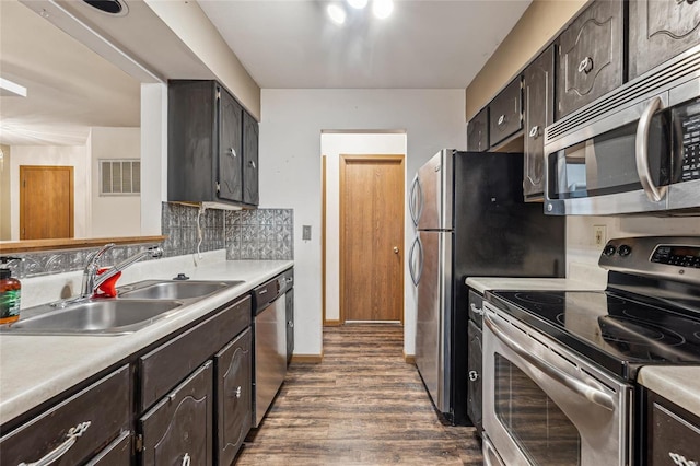 kitchen with sink, dark hardwood / wood-style floors, tasteful backsplash, dark brown cabinets, and stainless steel appliances