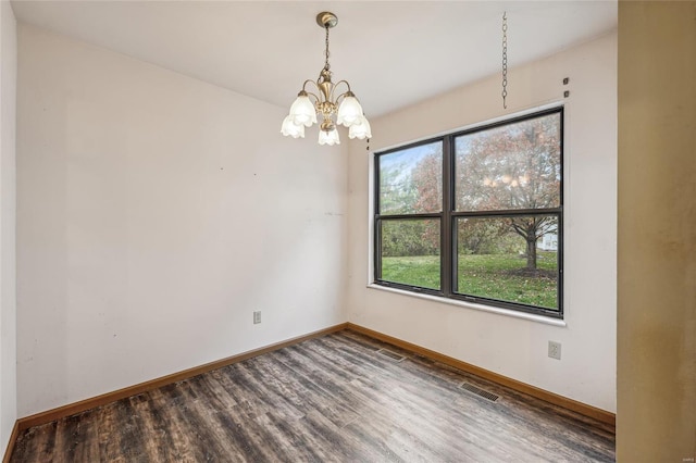 spare room featuring a chandelier and hardwood / wood-style floors