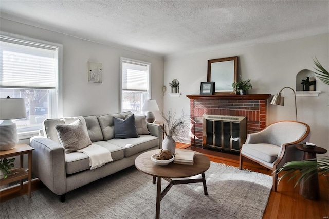 living room featuring wood-type flooring, a fireplace, and a textured ceiling