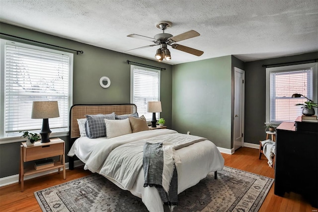 bedroom with a textured ceiling, light hardwood / wood-style flooring, and ceiling fan