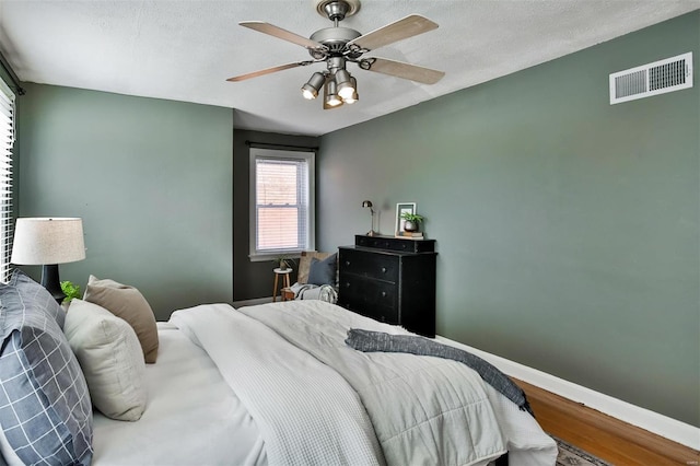 bedroom with wood-type flooring, a textured ceiling, and ceiling fan