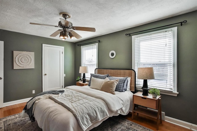 bedroom with a textured ceiling, dark hardwood / wood-style floors, and ceiling fan