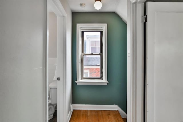 hallway with hardwood / wood-style flooring, plenty of natural light, a textured ceiling, and vaulted ceiling