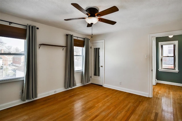 spare room featuring plenty of natural light, a textured ceiling, and light hardwood / wood-style flooring