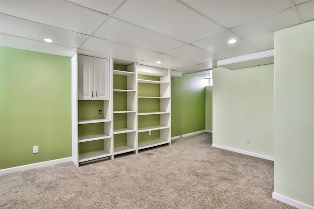 basement featuring light carpet and a paneled ceiling