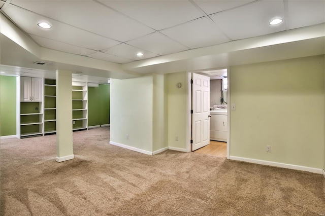 basement with washer / dryer, light colored carpet, and a drop ceiling