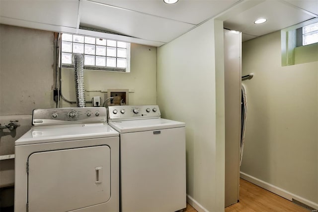 laundry area with washing machine and dryer and light wood-type flooring