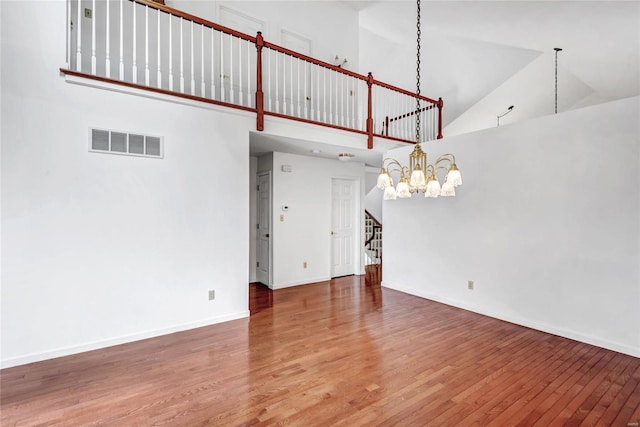 interior space featuring wood-type flooring, a high ceiling, and a chandelier