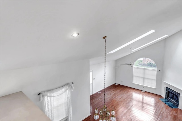 unfurnished living room featuring a fireplace, hardwood / wood-style floors, ceiling fan with notable chandelier, and lofted ceiling