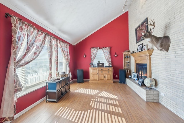 interior space with wood-type flooring, a fireplace, lofted ceiling, and crown molding