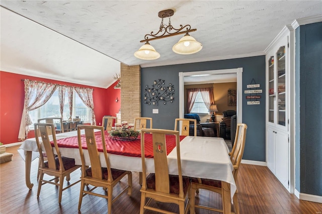 dining room featuring a textured ceiling, dark hardwood / wood-style flooring, crown molding, and vaulted ceiling